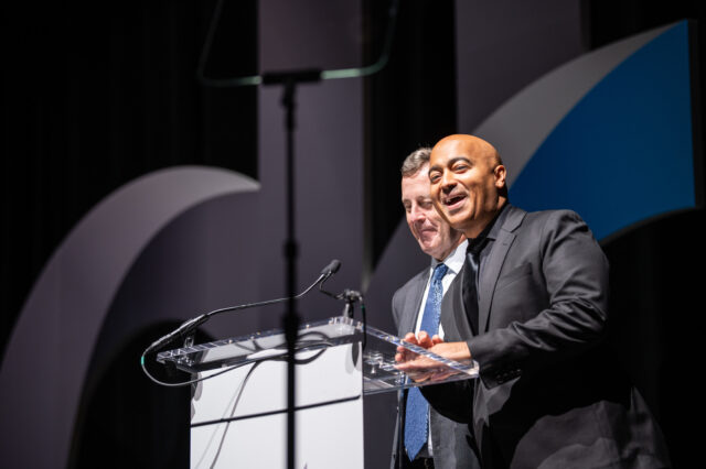 CDT board member Travis LeBlanc speaks from the podium at Tech Prom 2022, while board member Mark Seifert looks on.