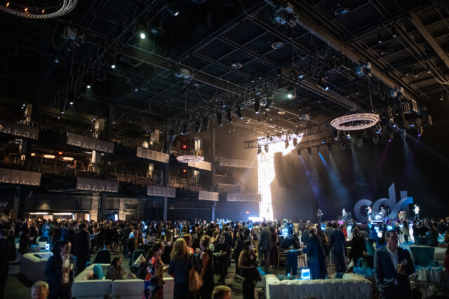 2022 Tech Prom guests fill the Anthem. People chatting across lounges, tables, and chairs while the band plays.