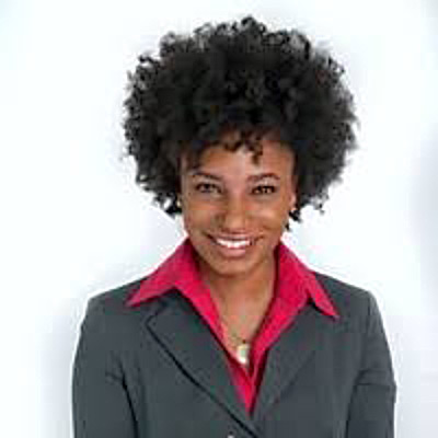 Damara Catlett. Principal, Raben Group. Wearing a red collared shirt and a dark grey suit, in front of a white backdrop.