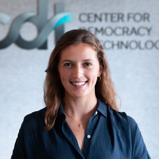 Isabel Linzer, smiling wearing a dark blue top and necklace in front of a CDT logo.