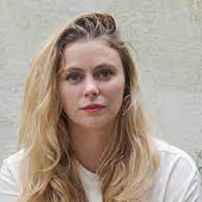 Camille Francois. Wearing a light colored shirt in front of a light colored background.