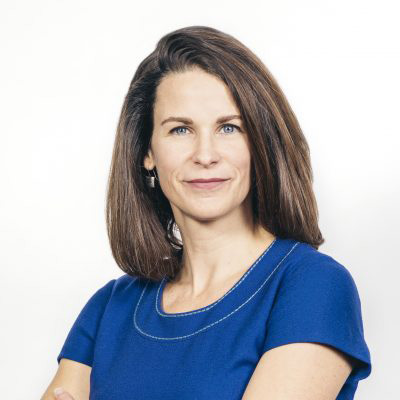 Lara Flint. Democracy Fund. Wearing a blue shirt in front of a white backdrop.