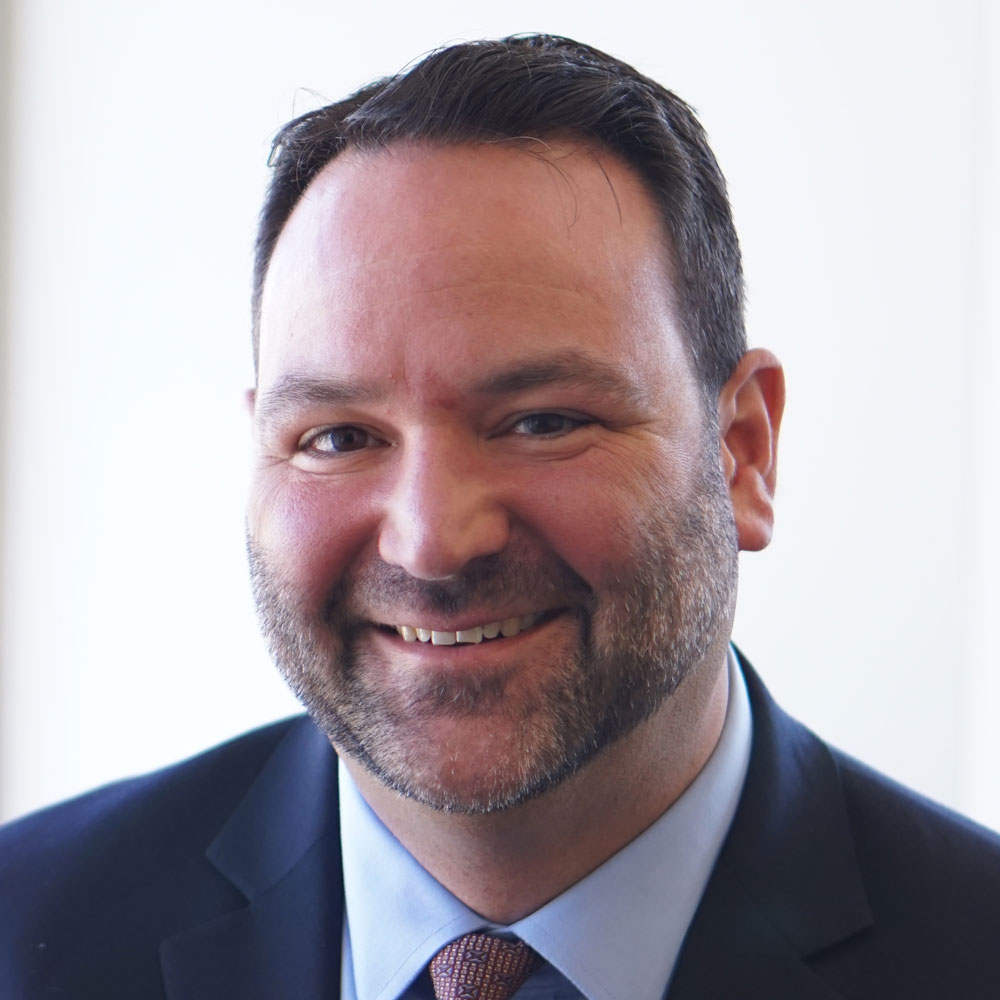 Gabe Rottman, smiling in front of a brightly lit window and office background.