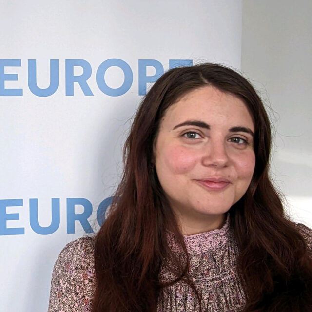 Giulia Papapietro, smiling in a pink textured top standing in front of the words "CDT Europe."