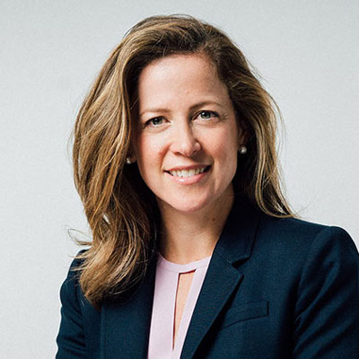 Miriam Vogel. EqualAI. Wearing a light purple shirt and a dark blue suit, in front of a light grey backdrop.