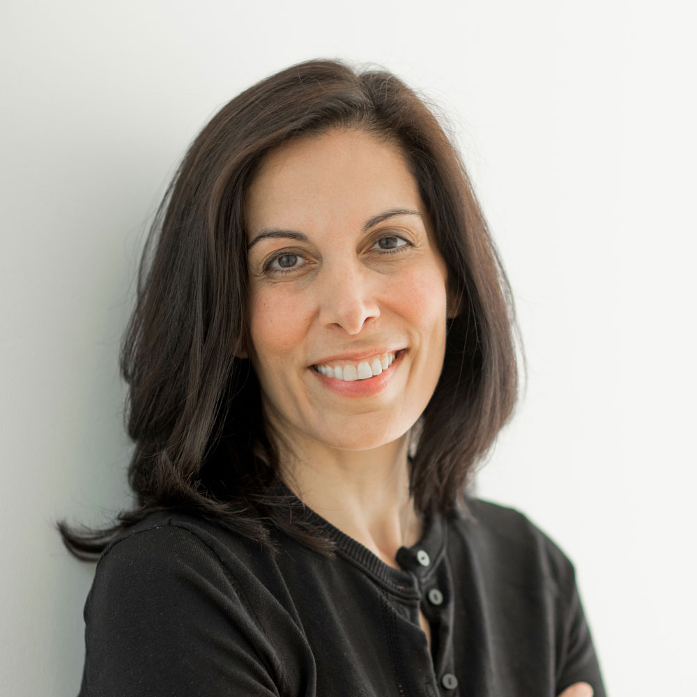 Nita Farahany, wearing a black top in front of a white background with arms crossed.