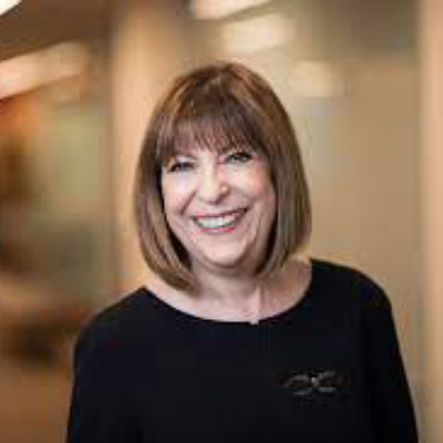 Lydia Parnes. Wilson Sonsini Goodrich & Rosati. Wearing a dark shirt in front of a light brown background.