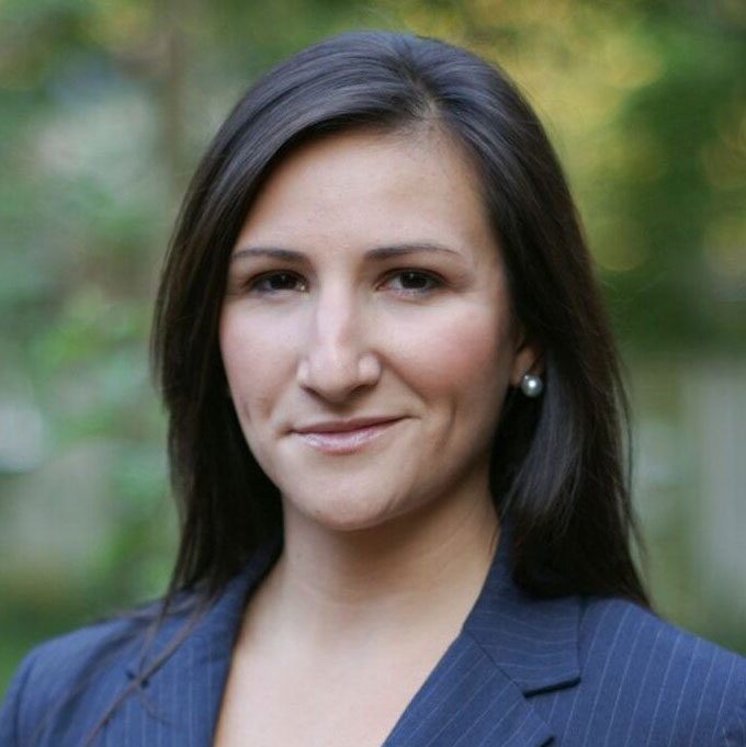 Rose Jackson, wearing a dark jacket and standing in a green outdoor setting.