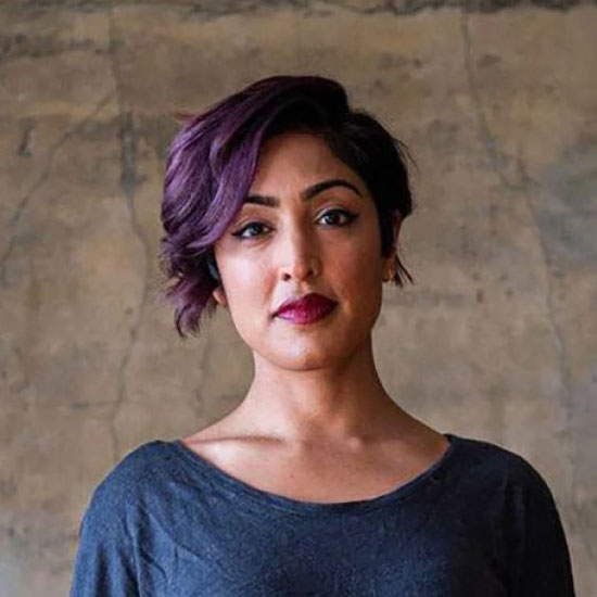 Rumman Chowdhury, wearing a dark top in front of a beige background.