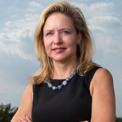 Shane Tews. American Enterprise Institute. Wearing a black shirt in front of a blue sky and green leafy background.