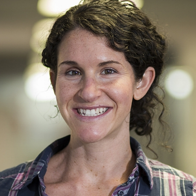 Jenny Davis, smiling wearing a patterned shirt in front of an indoor background.