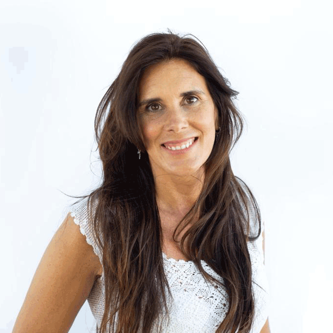 Laura Zommer, smiling in a white dress in front of a white background.