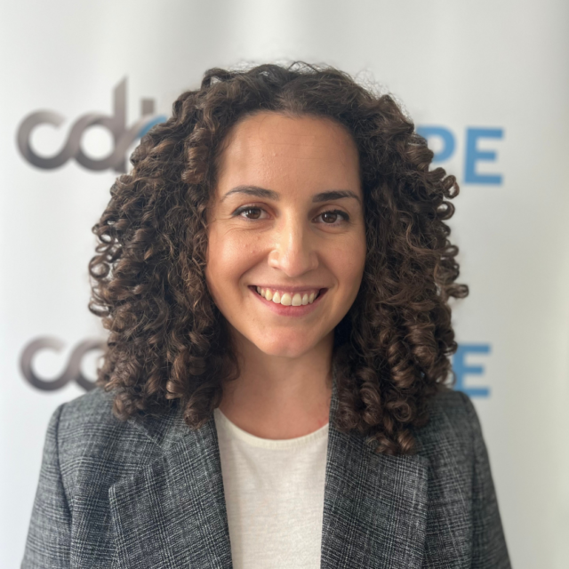 Silvia Lorenzo Perez, smiling in a white top and grey blazer, in front of a CDT Europe backdrop.